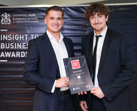 Two males wearing suits and holding a certificate.